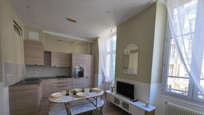 Una cocina compacta con electrodomésticos modernos, un comedor con mesa dispuesta para cuatro personas y un ventanal que proporciona luz natural.