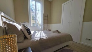 Un dormitorio con cama, ventana, armario y una escalera.