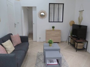 Ein Wohnzimmer mit Sofa, Couchtisch, TV-Schrank und einem Spiegel an der Wand.