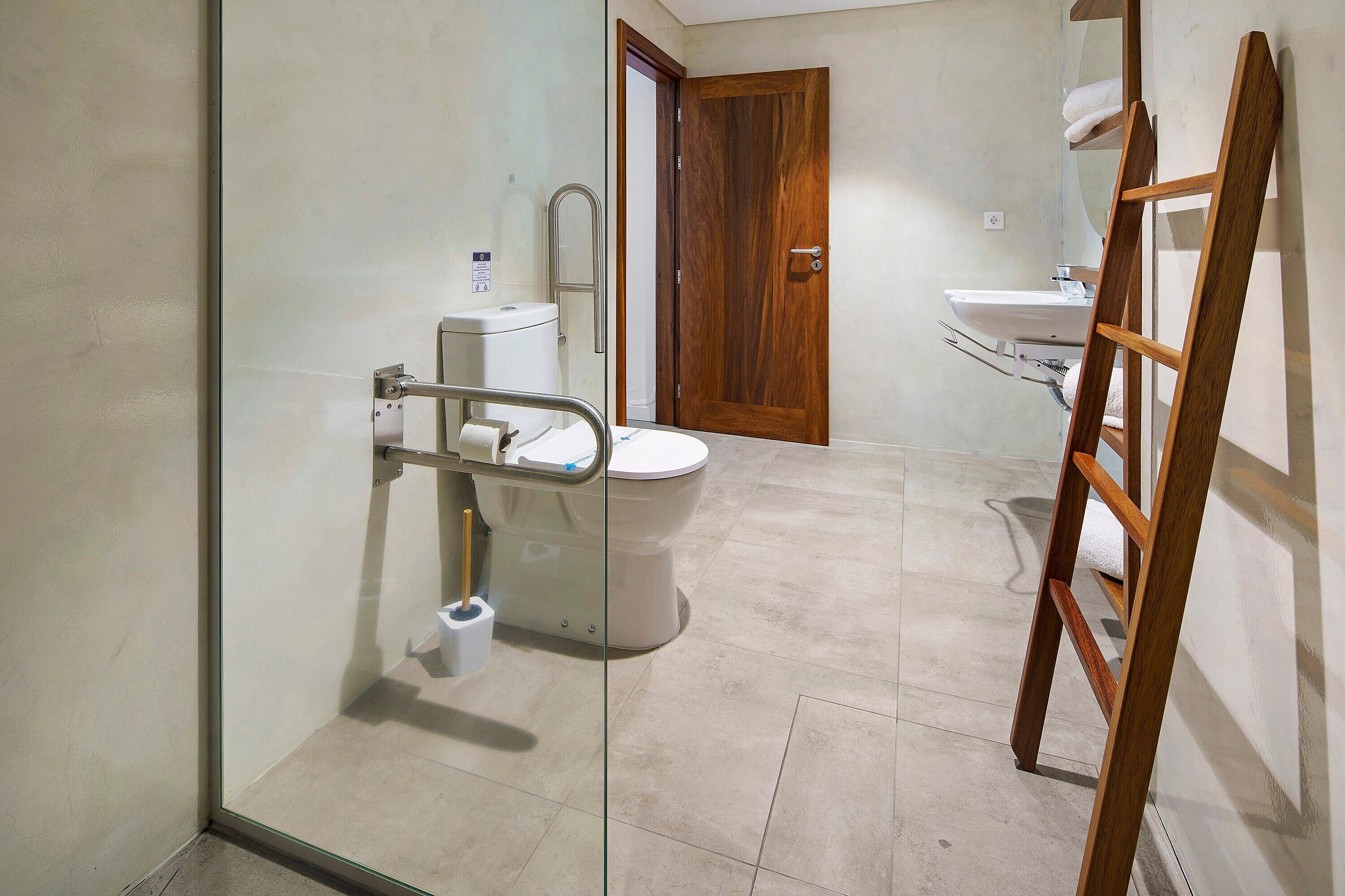 Een badkamer met toilet, wastafel en een houten trap.