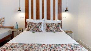 Una habitación de hotel con una cama grande, dos mesitas de noche, un cabecero de listones de madera y dos lámparas fijadas a la pared.