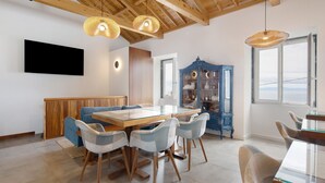 A dining area with a glass-top table, wooden chairs, and a blue cabinet with shelves. - Room 'Quarto 5 - Duplo Com Pátio' with Mountain View, Wi-Fi and Air Conditioning (Santa Bárbara)