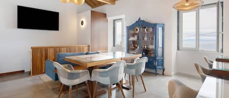 Un comedor con una mesa de vidrio, sillas de madera y un aparador azul con estantes.