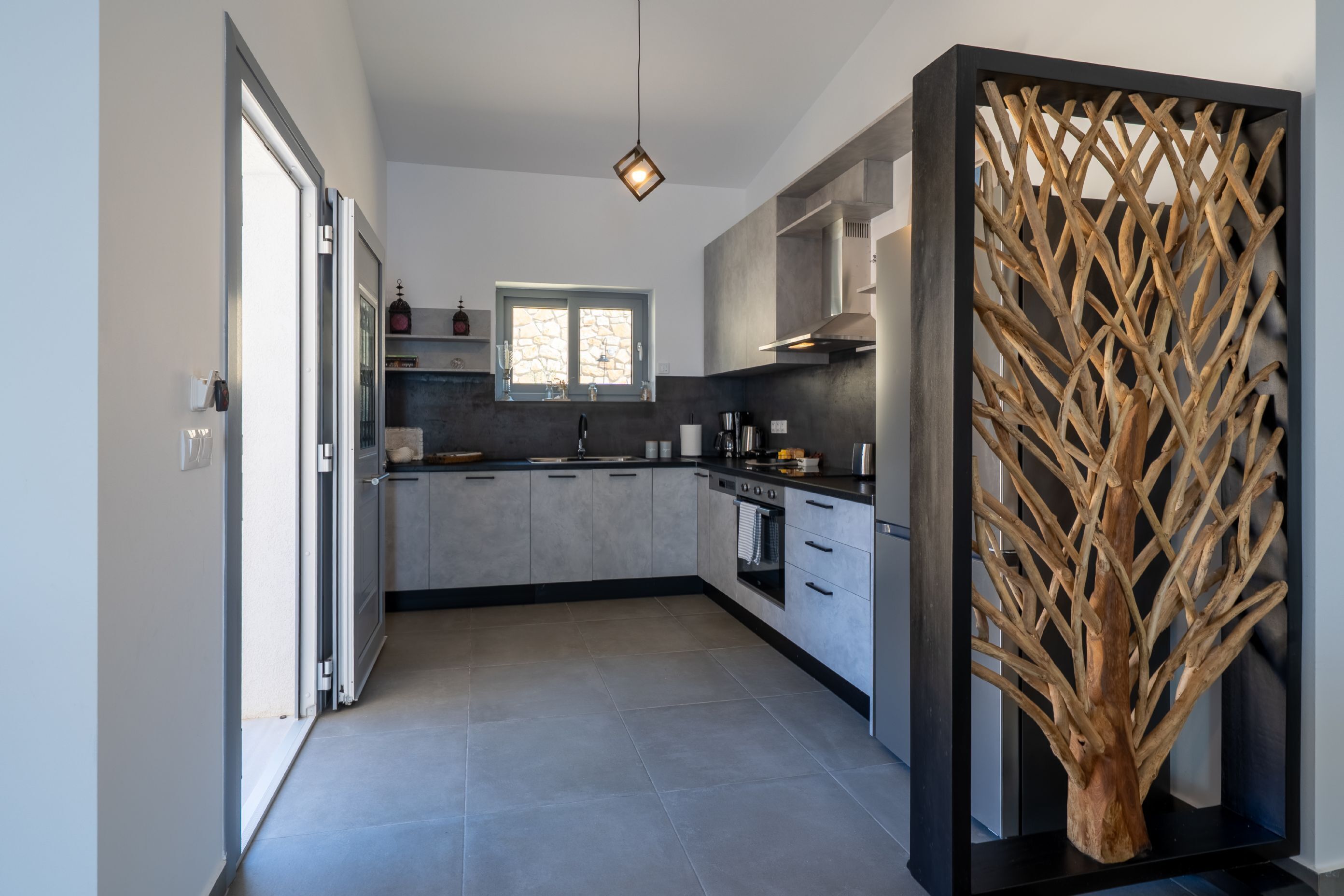 Una cucina moderna con mobili grigi, un piano di lavoro nero e una scultura decorativa a forma di albero.