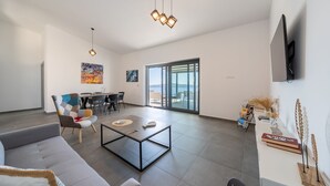 Een ruime woonkamer met een bank, salontafel en een eethoek met stoelen en een tafel.