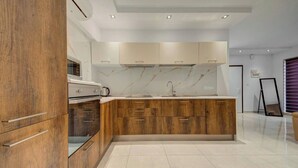 A modern kitchen with wooden cabinets, a marble backsplash, and a central island with a sink. - 3BR Penthouse w/ private Jacuzzi in St Julian’s (St. Julian`s)