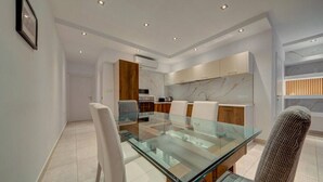A modern dining area with a glass table and white chairs, a kitchen with marble countertops, and recessed ceiling lighting. - 3BR Penthouse w/ private Jacuzzi in St Julian’s (St. Julian`s)