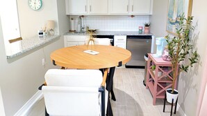 A compact kitchen with white cabinets, a round wooden table, and a small dining area. - Heavenly Hideaway Unit 1 (Daytona Beach)