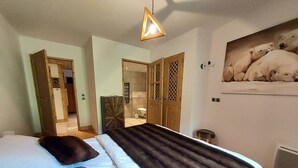 Une chambre à coucher avec un lit, une porte en bois, un miroir et un tableau représentant des ours polaires accroché au mur.