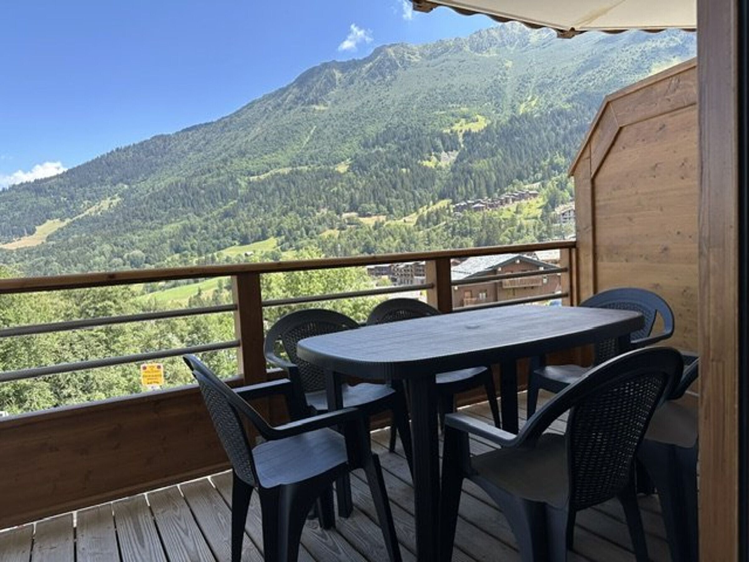 A wooden deck with a table and chairs overlooking a mountainous landscape.