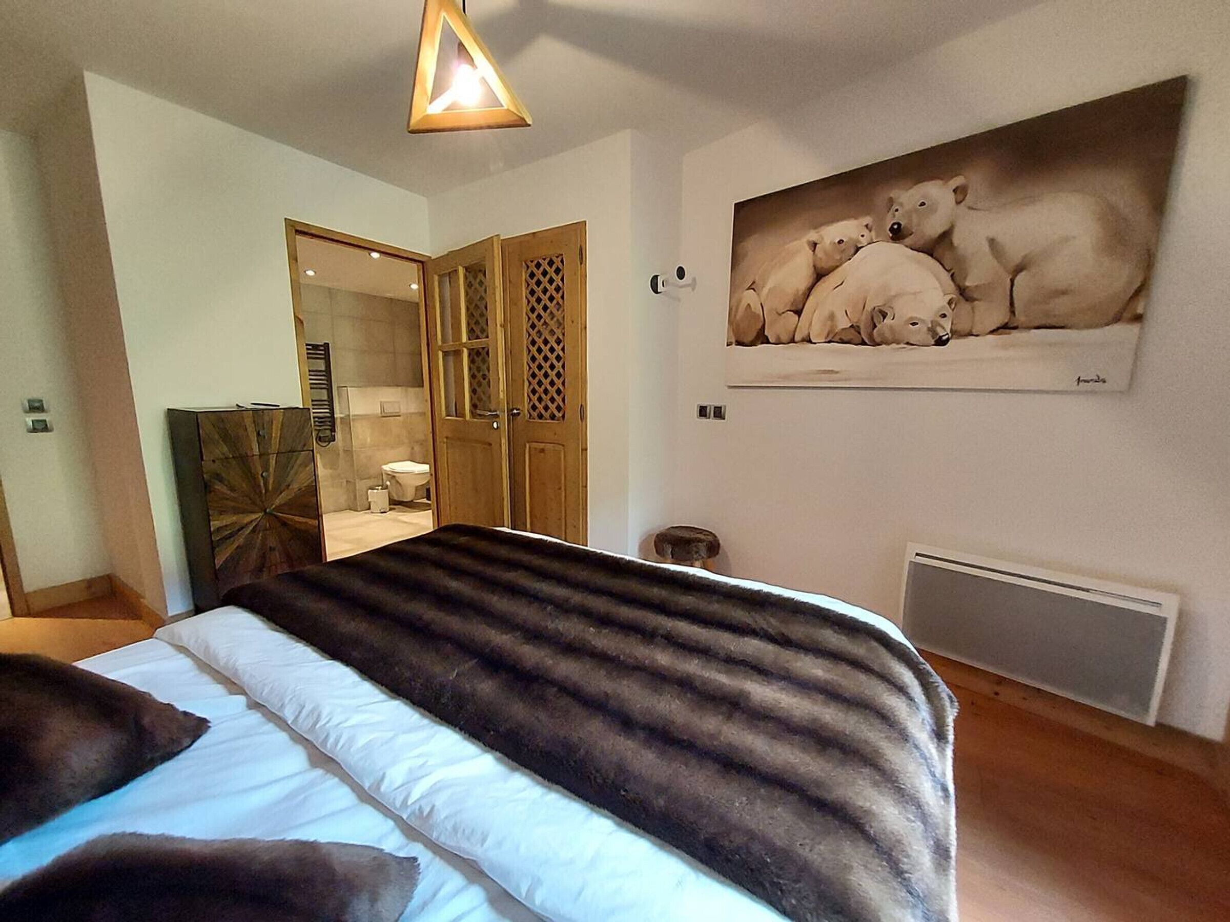 Un dormitorio con una cama, un cuadro de osos polares, un radiador y un armario de madera.