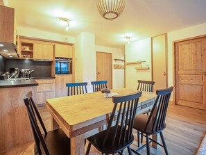 A modern kitchen with wooden cabinets, a built-in oven, and a dining area with a wooden table and chairs. - Cozy 4-person apartment in Valmorel with balcony and parking (Valmorel)