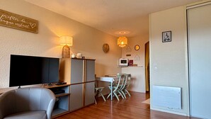 Un salon équipé d’un téléviseur à écran plat, d’un canapé, d’une table à manger avec des chaises et d’un coin cuisine avec un four à micro-ondes.