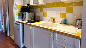 Une cuisine compacte équipée d’un évier, d’un four à micro-ondes et de placards.