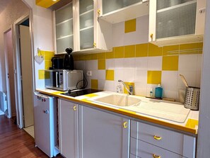 Cocina compacta con lavabo, microondas y armarios.