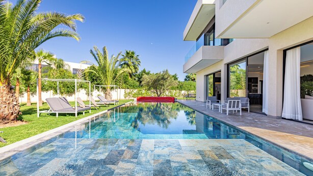 A modern pool area with clear water, lounge chairs, and a red barrier. - Beautiful villa with swimming pool at Argan Golf Resort (Marrakesh)