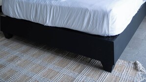 Quarto moderno com uma cama grande, cabeceira preta e uma escultura decorativa de um pássaro.