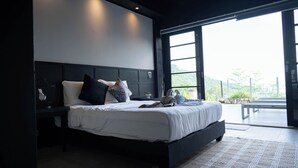 Quarto moderno com uma cama grande, mesa de cabeceira, janela com vista para o verde e luminária no teto.
