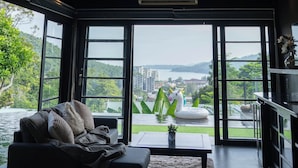 Uma sala de estar moderna com uma janela grande, um sofá, uma mesa de centro e um lustre.