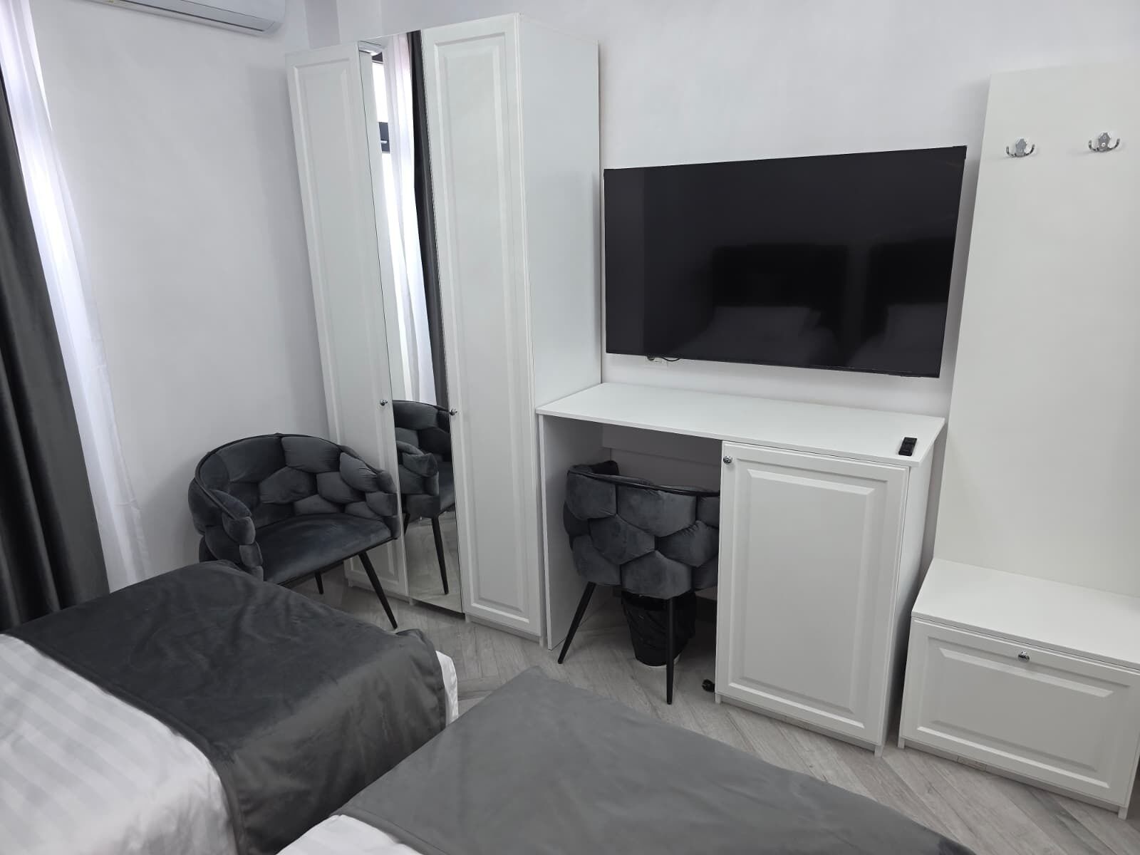 Een moderne hotelkamer met een bed, een bureau met een televisie, een stoel en een kledingkast.