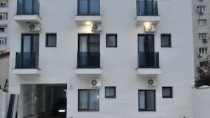 En bygning med flere etager, altaner, airconditionanlæg og parkeringsplads.