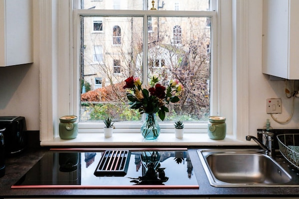A kitchen with a window, a sink, and a stove.