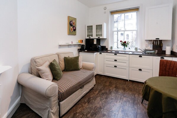 Un espace de vie compact comprenant un canapé, une kitchenette et une fenêtre.