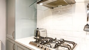 Une cuisine moderne équipée d’une cuisinière à gaz, d’un grille-pain et d’une hotte aspirante en acier inoxydable.