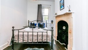 Une chambre à coucher avec un lit, une cheminée et une fenêtre avec des rideaux.