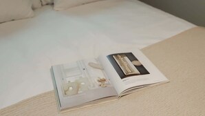 A magazine on a bed with a white cover. - Dam Residence's Heritage Rooms (Zaandam)