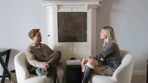 Two people seated in a modern room with a fireplace, a small table, and a trash bin. - Dam Residence's Signature Suites (Zaandam)