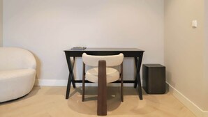 A small room with a white chair, a black table, and a black speaker. - Dam Residence's Signature Suites (Zaandam)