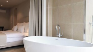 A modern bathroom with a freestanding bathtub, a large mirror, and a shower area. - Dam Residence's Signature Suites (Zaandam)