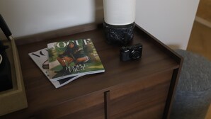 Ein Nachttisch aus Holz mit einer Kamera und Zeitschriften.