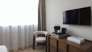 Ein Hotelzimmer mit einem Holztisch, einem Stuhl, einem Flachbildfernseher, einer Kaffeemaschine, einer Tasse und einem Buch mit dem Titel "Live Beautiful".