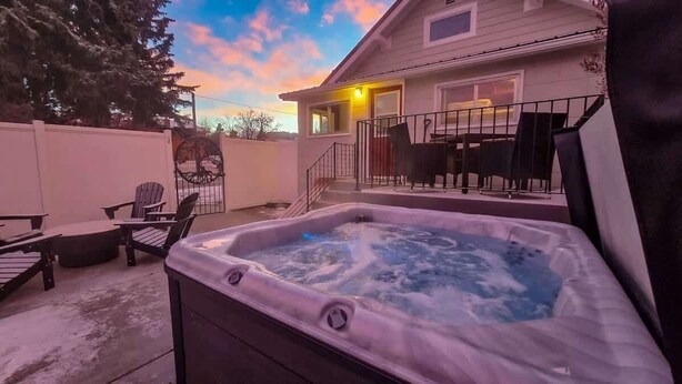 A hot tub in a backyard with chairs and a table, surrounded by a fence and a house. - The Speakeasy-Hot Tub-Pet Friendly-Downtown-AC (Red Lodge)