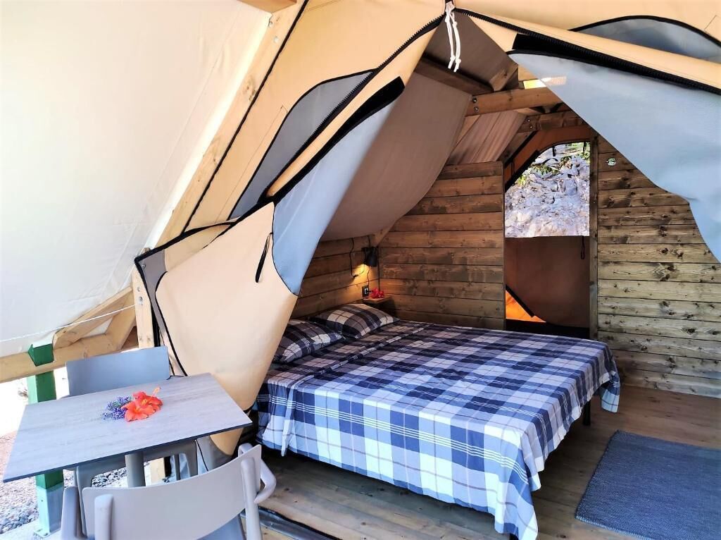 A cozy tent with a bed, a table, and a chair.