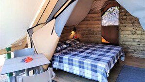 A cozy tent with a bed, a table, and a chair.
