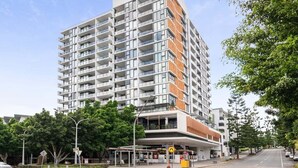 Un hôtel moderne à plusieurs étages, doté de balcons, d’une entrée couverte et offrant une vue sur un ciel dégagé.