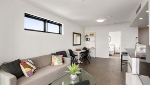 Un salon moderne avec un canapé, une table basse en verre et un coin repas comprenant des chaises et une table.