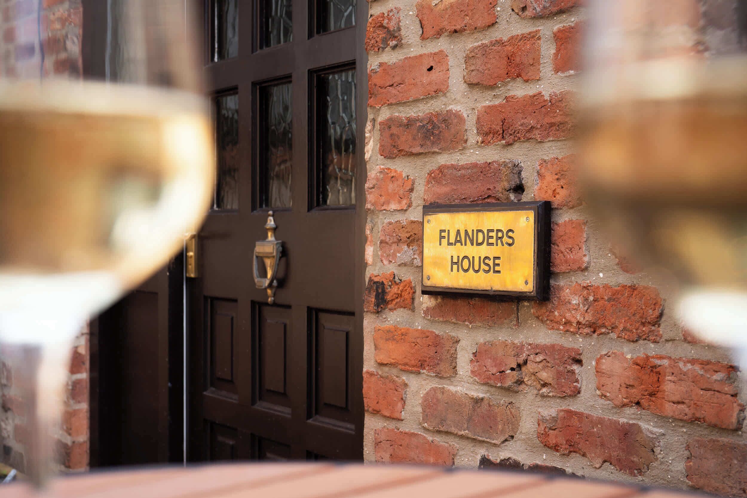 Un muro de ladrillo con un letrero que dice 'Flanders House'.