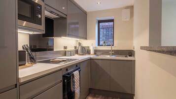 A modern kitchen with stainless steel appliances, a built-in oven, and a window with a view of the outside.