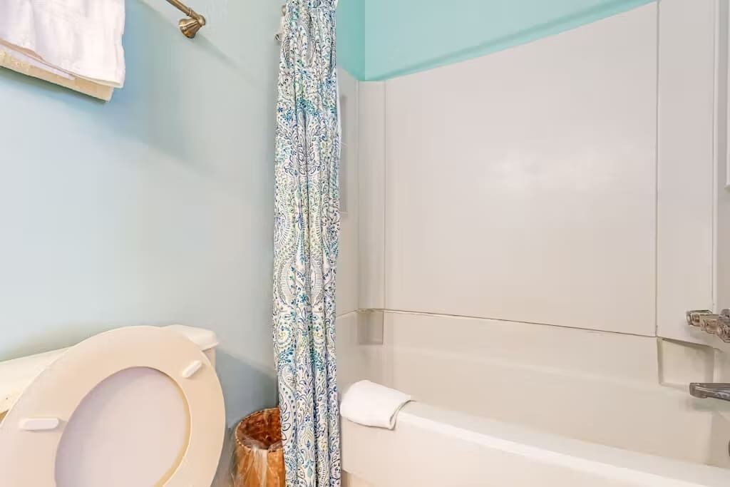 A bathroom with a toilet, a bathtub, and a shower curtain.