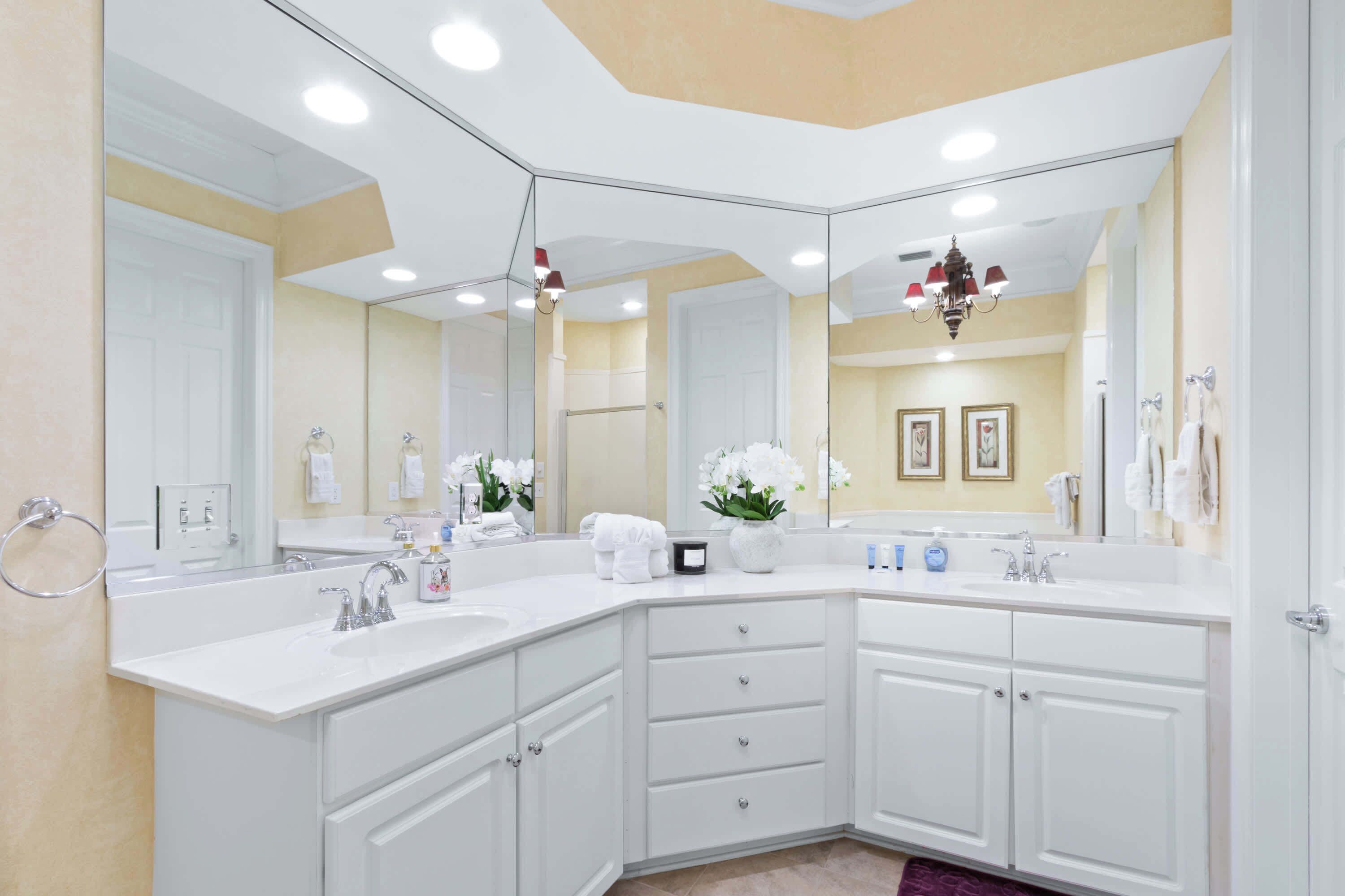 A modern bathroom with a large mirror, white cabinetry, and a vanity area.
