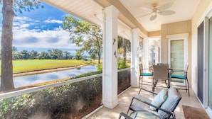 A covered porch with a view of a lake and greenery, furnished with chairs and a table. - Luxury 3 Bed 3 Bath Resort Beaches Pool Golf (Gulf Shores)
