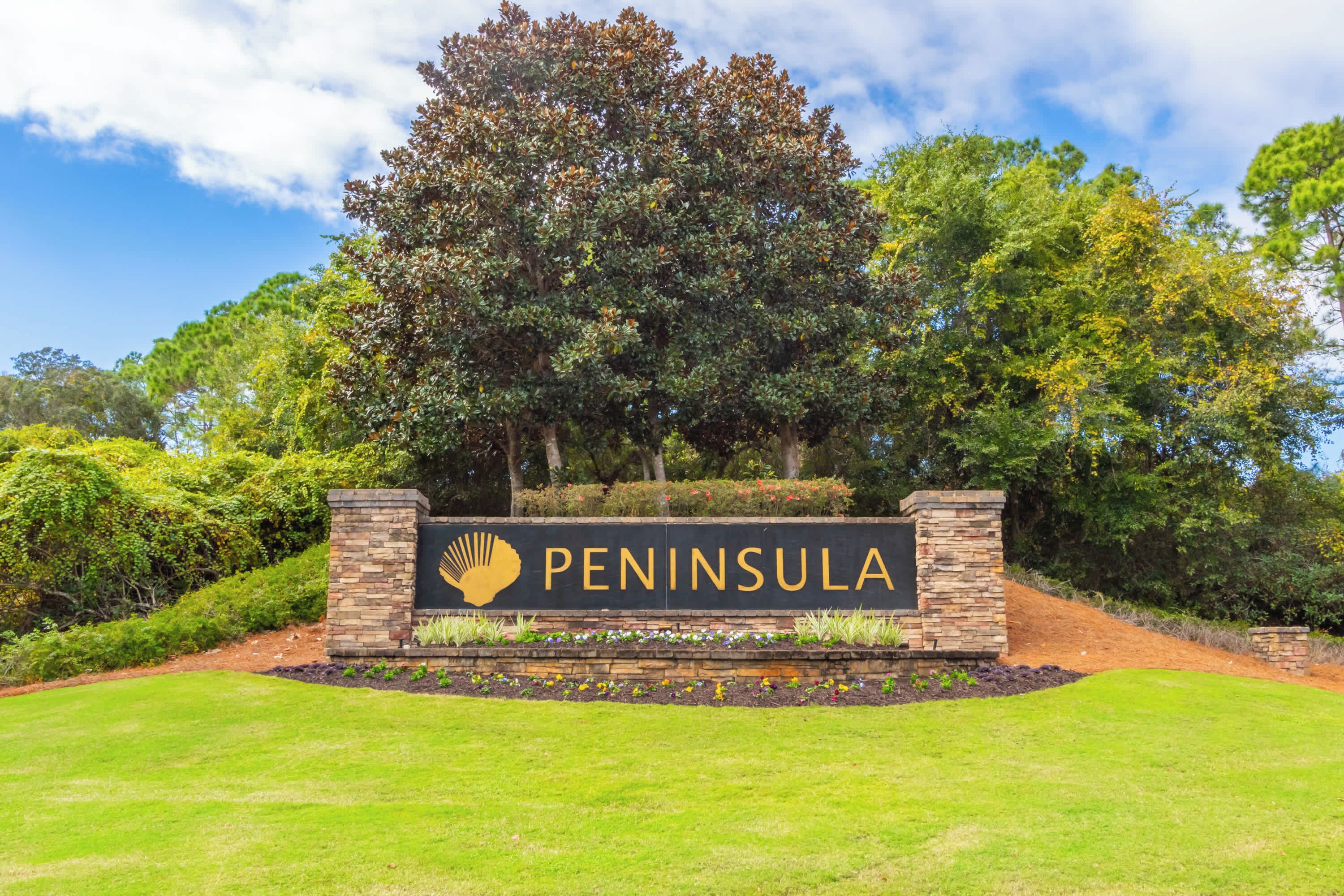 Un panneau sur lequel figure le mot « PENINSULA » et un symbole représentant un palmier, le tout entouré de verdure et sous un ciel dégagé.