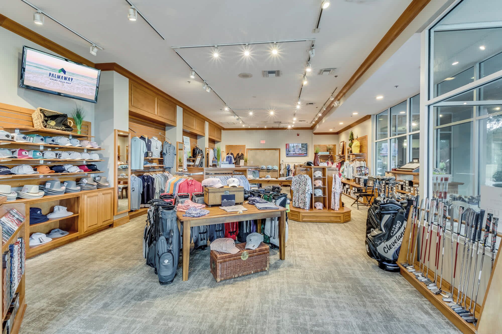 A well-lit retail store with various clothing items, hats, and bags on display.