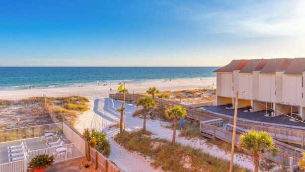 A beachfront hotel with a sandy beach, palm trees, and a clear view of the ocean. - Gulf View 2 Bed Beaches Pool Dining and Fun (Gulf Shores)