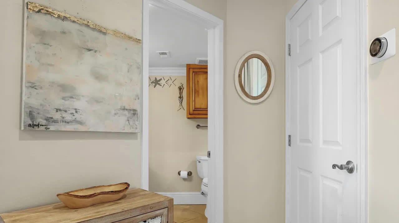 A bathroom with a wooden vanity, a white toilet, and a wall-mounted mirror.