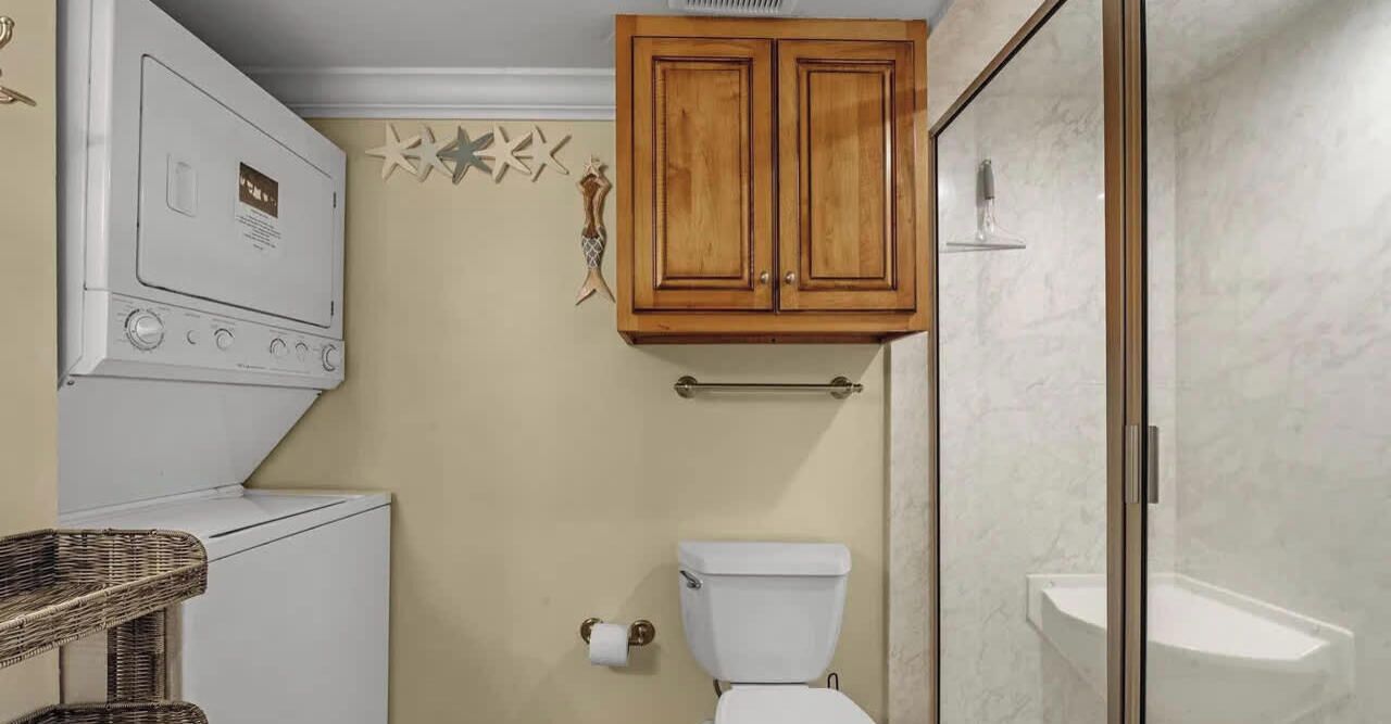 A compact bathroom with a toilet, a small sink, and a shower area.